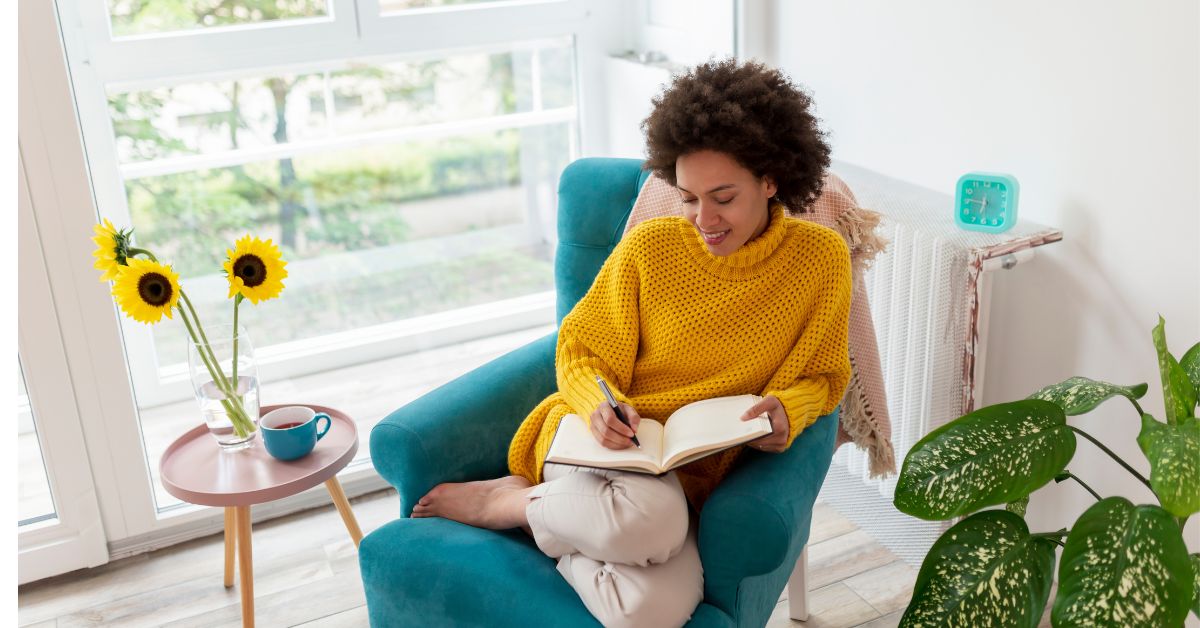 blogger writing a blog post on an aqua-colored chair.